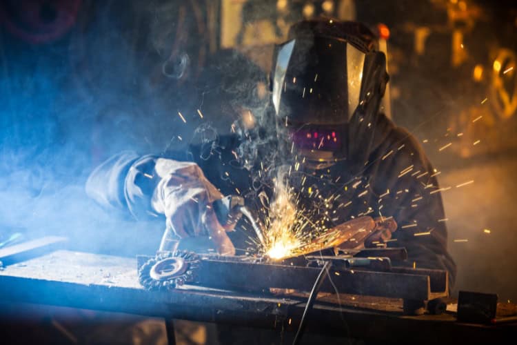 A welder is doing fabrication work on a metal component