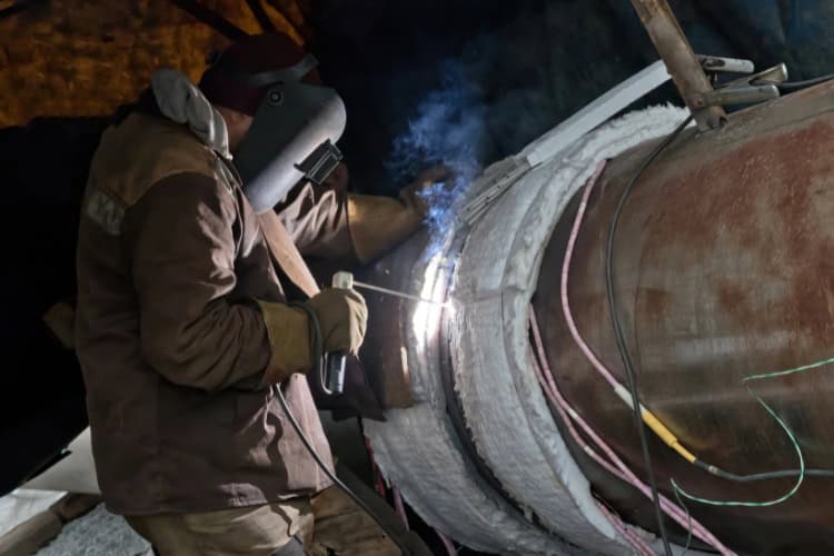 A welder performing a repair on a large metal pipe