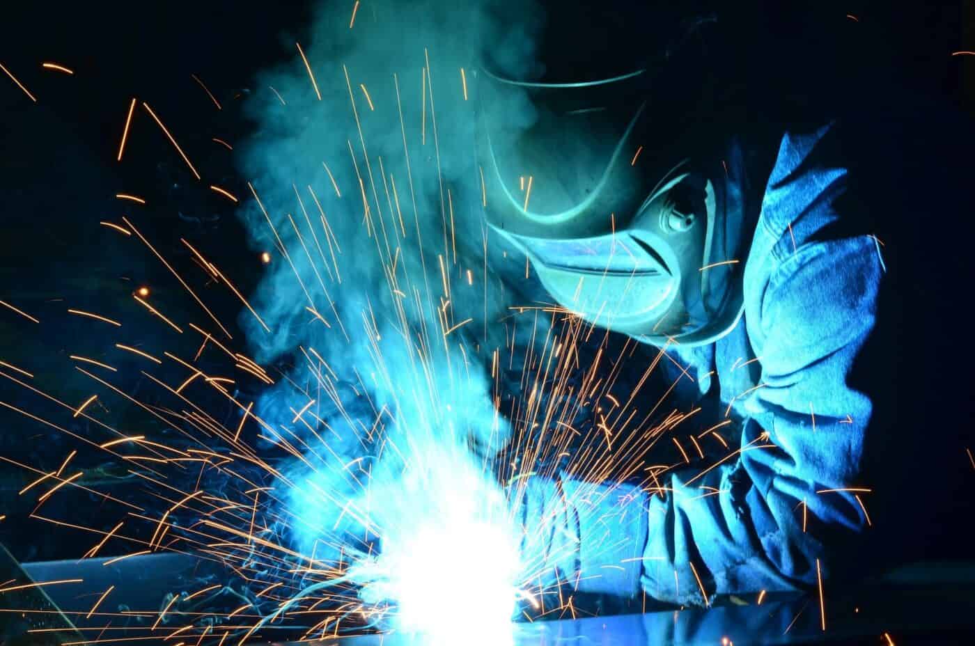 Sparks fly as a welder wearing protective gear works on a weld